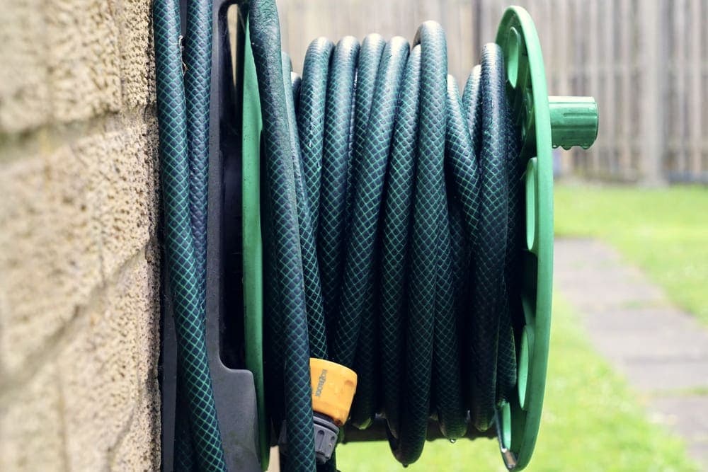 A coiled hose on a reel mounted outdoors