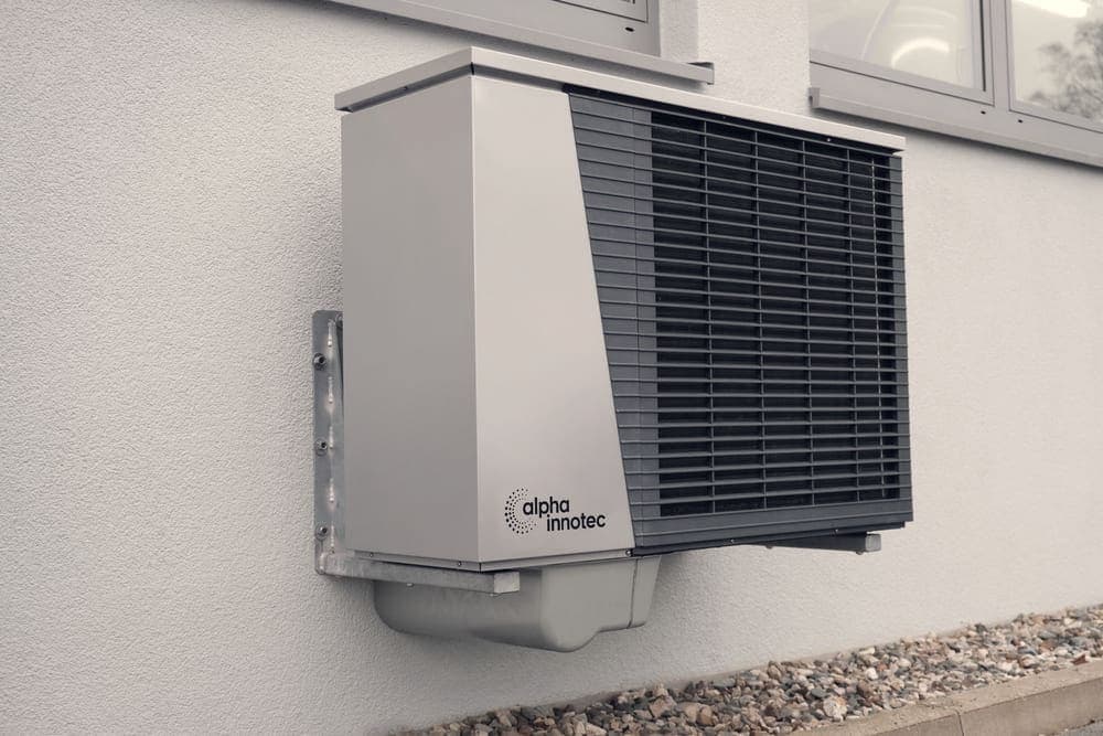 An outdoor heat pump unit beside a wall