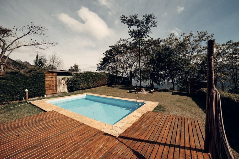 A swimming pool at dusk beside a wooden deck