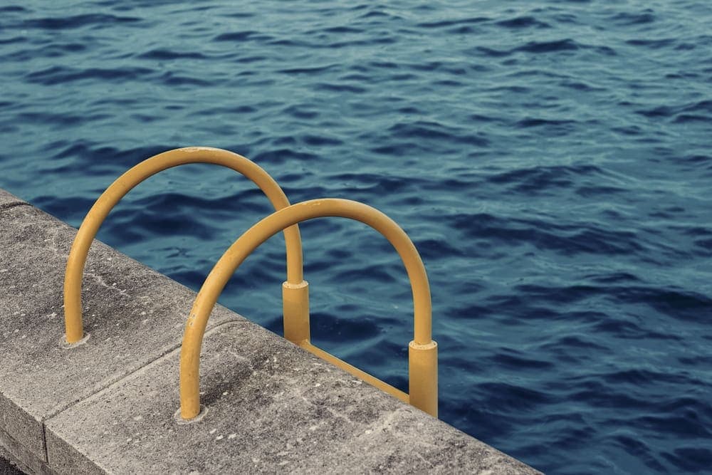 A handrail beside blue pool water