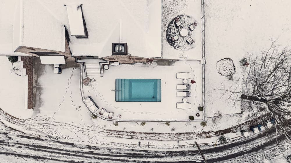 A covered swimming pool in a snow-covered garden