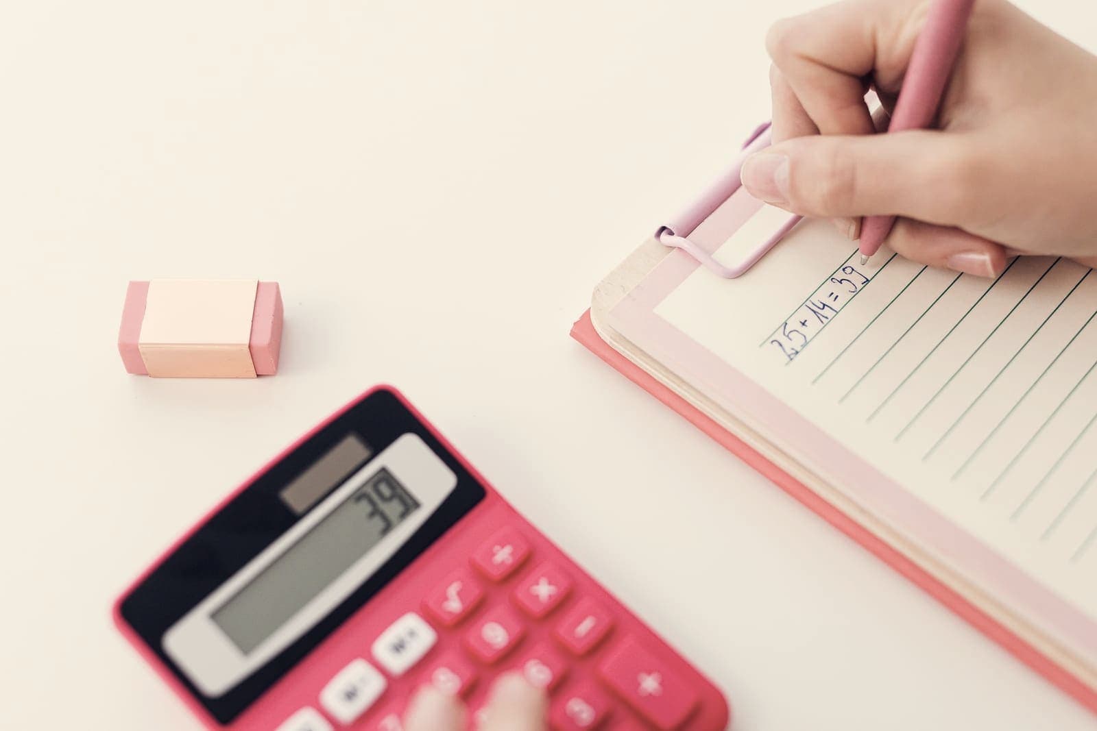 A calculator and a notebook of handwritten figures on a desk
