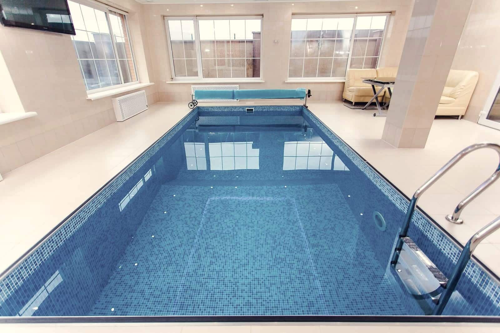 A backyard swimming pool photographed in soft low light, its surface partly covered